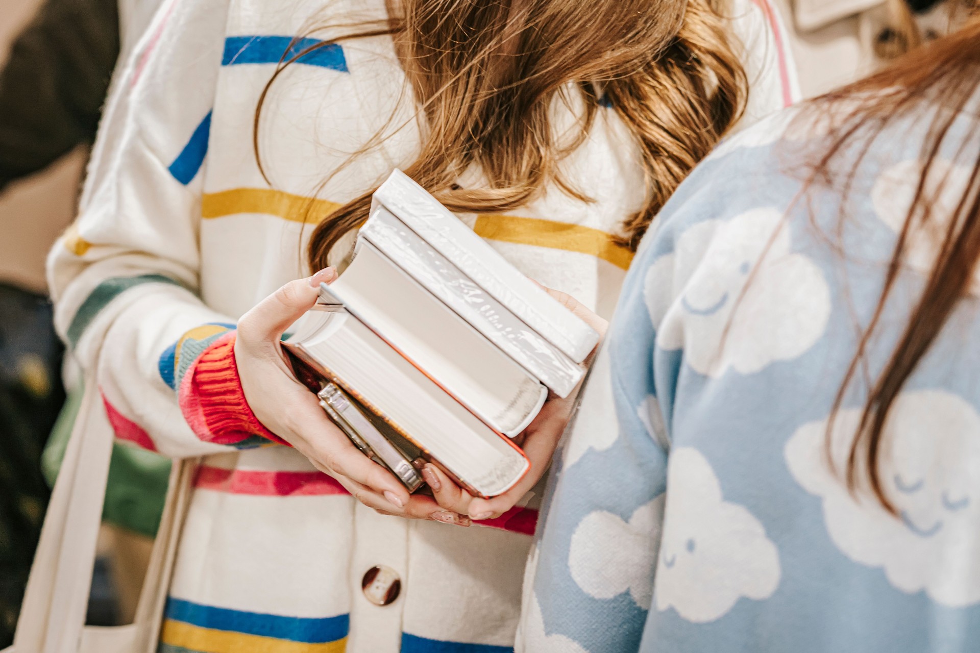 Abstract young girl in bookstore with pile of books in her hands. Concept of education, reading, hobby